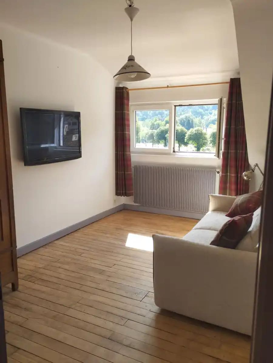 Chambre avec lit double et coin salon avec télévision